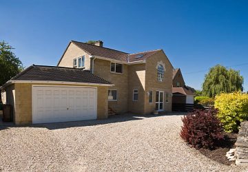 New build home in the picturesque Cotswolds, gravel drive and clear blue sky on a perfect summers day.