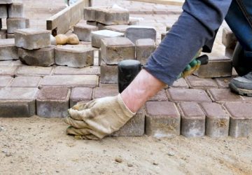 Paving slabs.The hands of a road worker are shifting paving slabs, repairing the road surface.